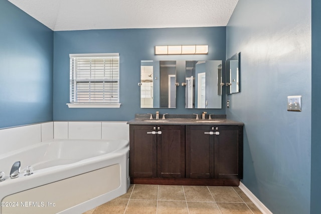 bathroom featuring tile patterned floors, a washtub, vanity, and a textured ceiling