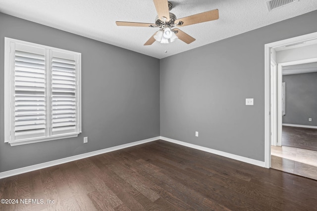 empty room with a textured ceiling, dark hardwood / wood-style flooring, and ceiling fan