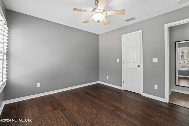 empty room featuring a textured ceiling, ceiling fan, and dark wood-type flooring