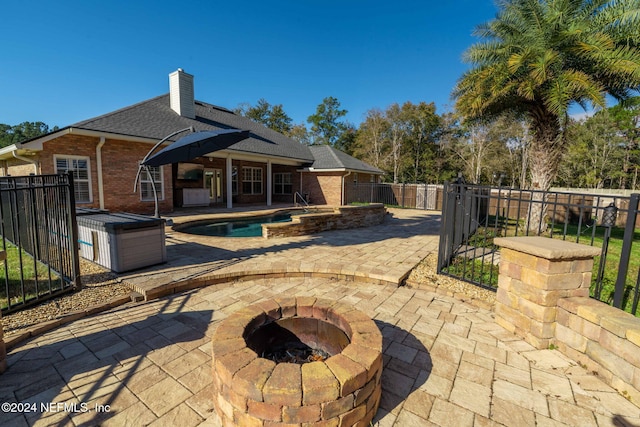 rear view of property featuring a pool with hot tub, a patio, and an outdoor fire pit