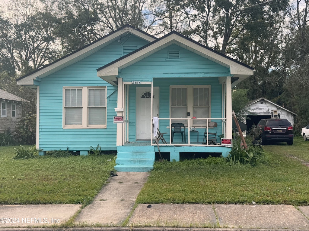 bungalow-style home featuring covered porch and a front lawn