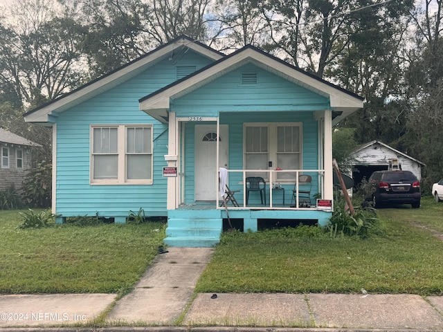 bungalow-style home featuring covered porch and a front lawn