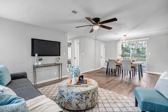 living room with ceiling fan with notable chandelier and hardwood / wood-style flooring