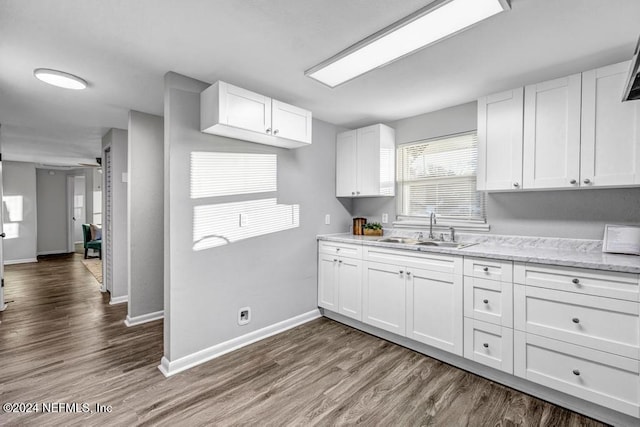 kitchen with dark hardwood / wood-style flooring, light stone countertops, sink, and white cabinets