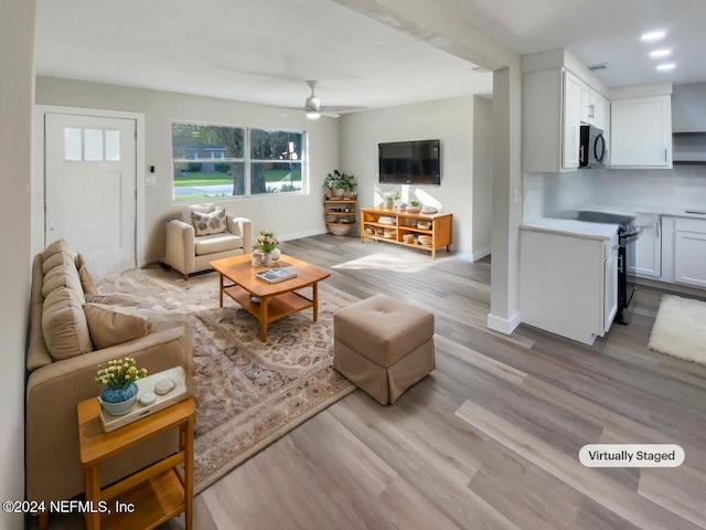 living room with ceiling fan and light hardwood / wood-style floors