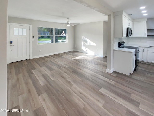 interior space featuring light hardwood / wood-style floors, ceiling fan, electric range oven, and white cabinetry