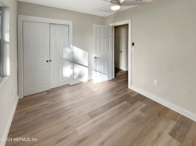 unfurnished bedroom featuring ceiling fan, light wood-type flooring, and a closet