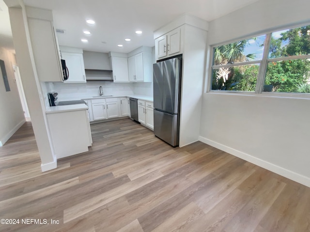 kitchen with backsplash, sink, appliances with stainless steel finishes, light hardwood / wood-style floors, and white cabinetry