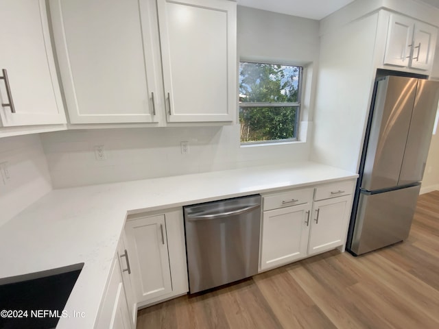 kitchen with light wood-type flooring, stainless steel appliances, and white cabinetry