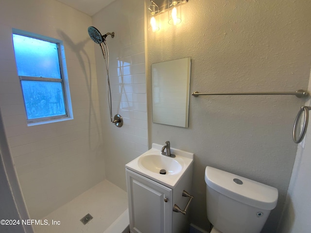 bathroom with tiled shower, vanity, and toilet