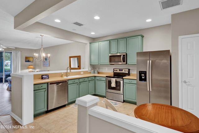 kitchen featuring kitchen peninsula, appliances with stainless steel finishes, ceiling fan with notable chandelier, sink, and pendant lighting