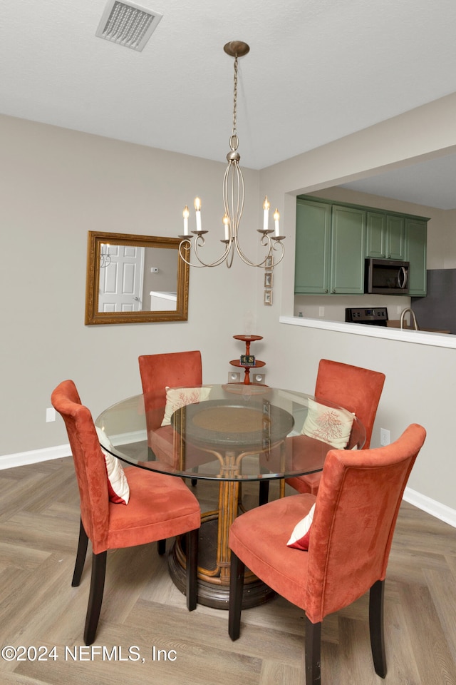 dining room featuring a chandelier and parquet flooring