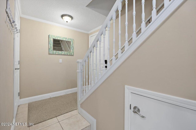 stairway with tile patterned flooring, a textured ceiling, and crown molding