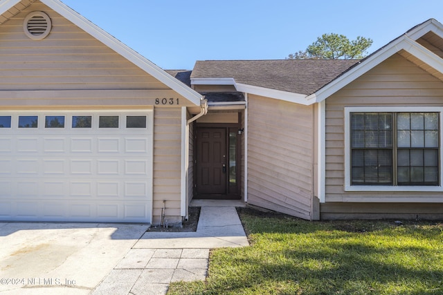 property entrance with a lawn and a garage