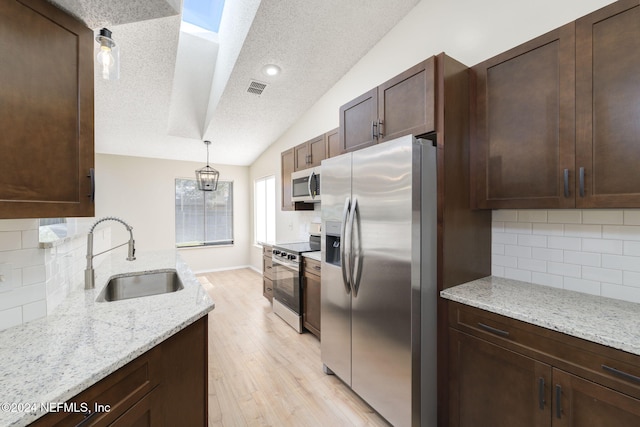 kitchen with sink, hanging light fixtures, backsplash, lofted ceiling, and appliances with stainless steel finishes