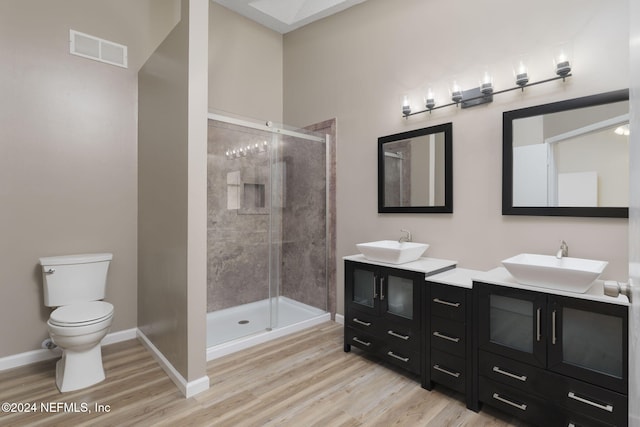 bathroom featuring a shower with door, vanity, wood-type flooring, and toilet