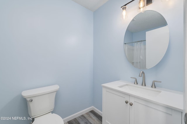 bathroom with hardwood / wood-style floors, vanity, a textured ceiling, and toilet