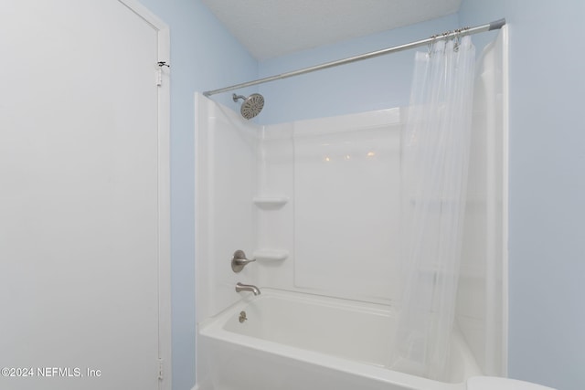 bathroom with a textured ceiling and shower / bathtub combination with curtain