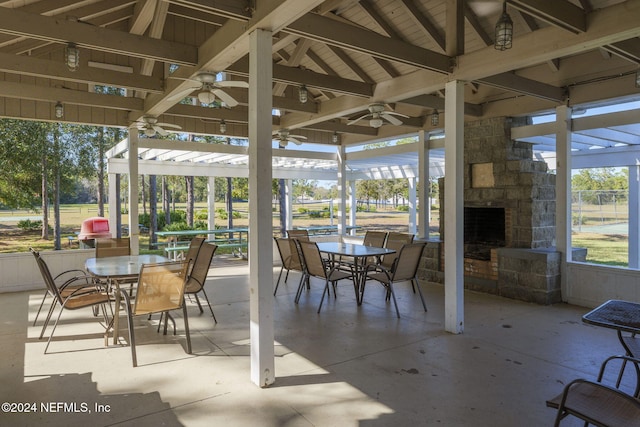 sunroom featuring vaulted ceiling with beams, an outdoor stone fireplace, and ceiling fan