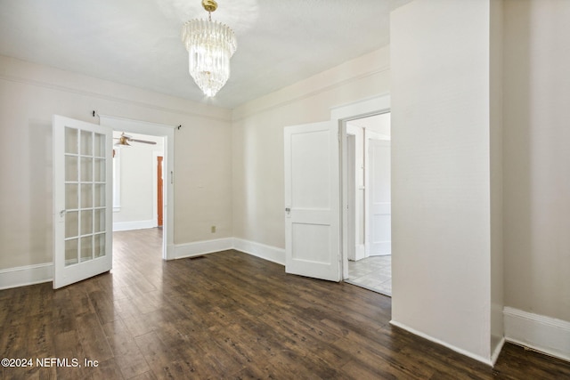 empty room featuring ceiling fan with notable chandelier and dark hardwood / wood-style flooring