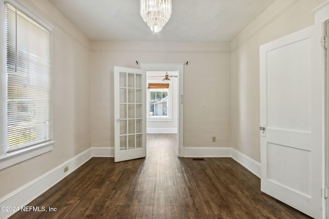 unfurnished room featuring french doors, ceiling fan with notable chandelier, dark hardwood / wood-style floors, and plenty of natural light