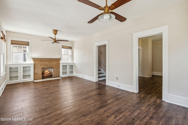 unfurnished living room featuring ceiling fan, a fireplace, and dark wood-type flooring