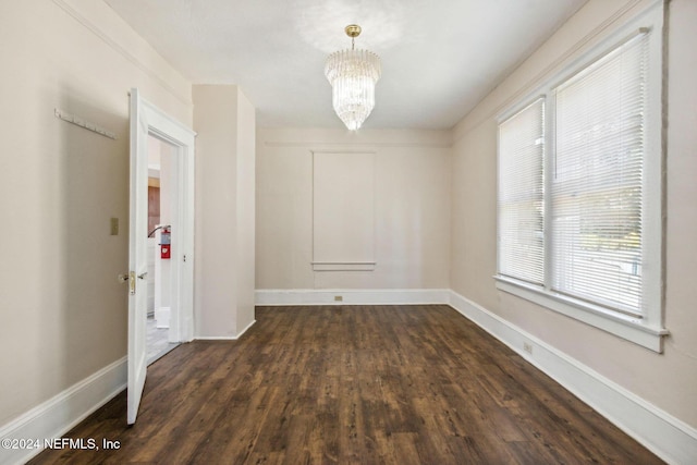 spare room featuring dark hardwood / wood-style floors and a notable chandelier