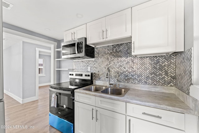 kitchen with backsplash, white cabinets, sink, light hardwood / wood-style flooring, and stainless steel appliances