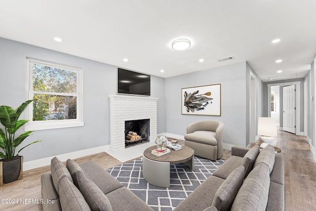 living room with hardwood / wood-style flooring and a brick fireplace