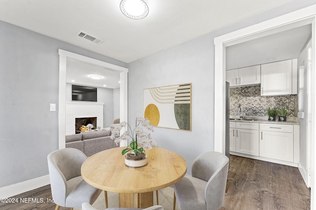 dining space with a fireplace, dark wood-type flooring, and sink