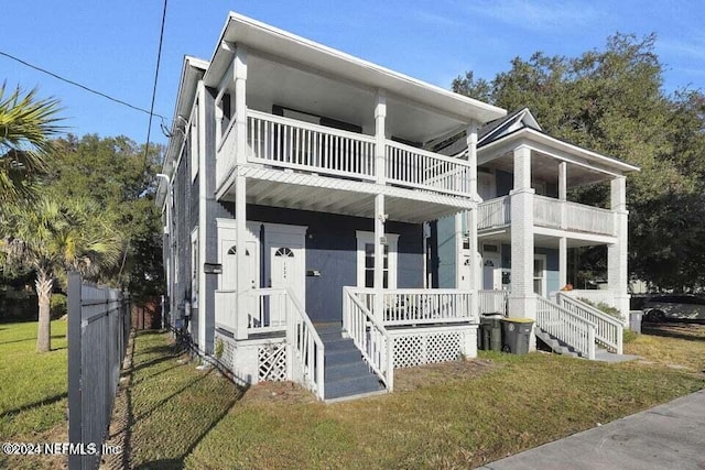 view of front facade featuring a balcony, covered porch, and a front yard