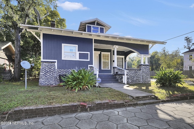 bungalow-style house featuring covered porch and a front lawn