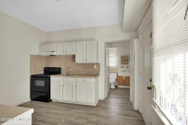 kitchen featuring sink, tasteful backsplash, black / electric stove, light hardwood / wood-style floors, and white cabinets