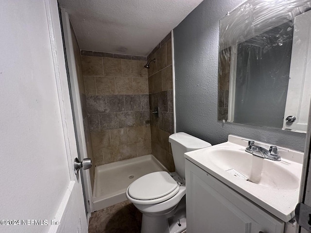 bathroom featuring tiled shower, vanity, a textured ceiling, and toilet