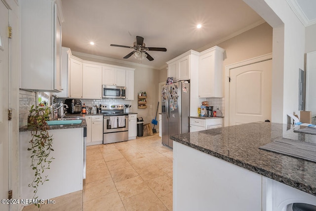 kitchen featuring white cabinetry, ceiling fan, stainless steel appliances, dark stone countertops, and ornamental molding