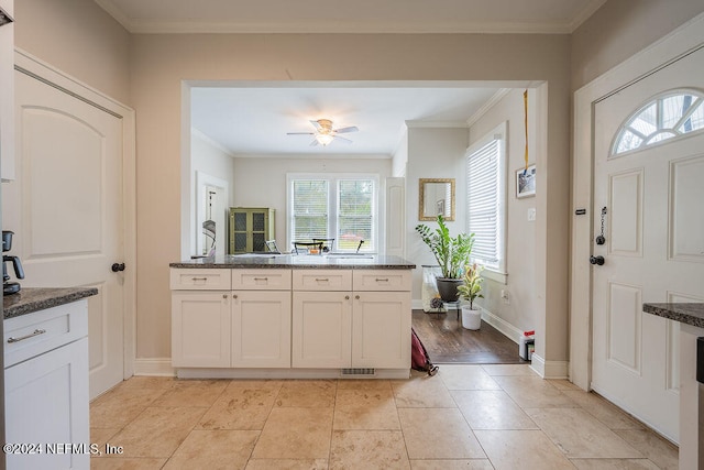 kitchen featuring ceiling fan, crown molding, dark stone counters, white cabinets, and light wood-type flooring