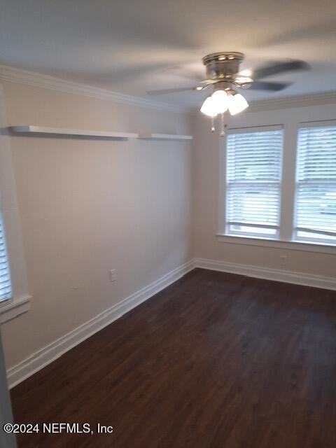 unfurnished room featuring ceiling fan, dark hardwood / wood-style flooring, and crown molding