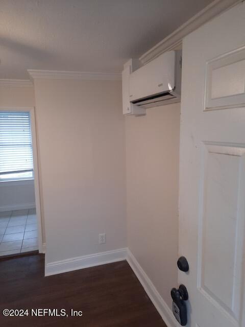 clothes washing area with a wall mounted air conditioner, dark hardwood / wood-style floors, and crown molding