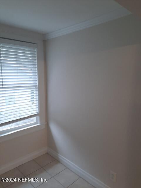 spare room featuring ornamental molding and light tile patterned flooring