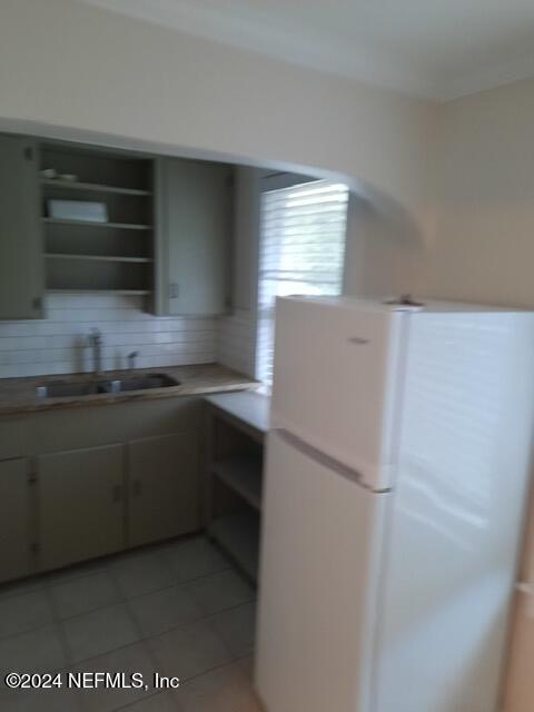 kitchen featuring tile patterned floors, sink, and white fridge