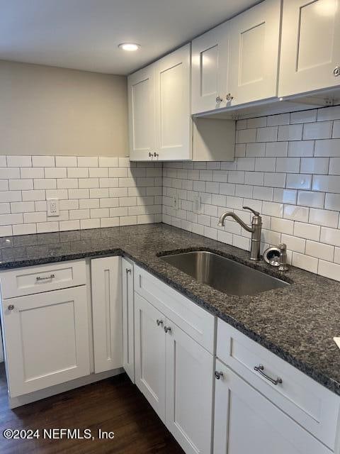 kitchen featuring sink, white cabinets, dark stone counters, and dark hardwood / wood-style floors