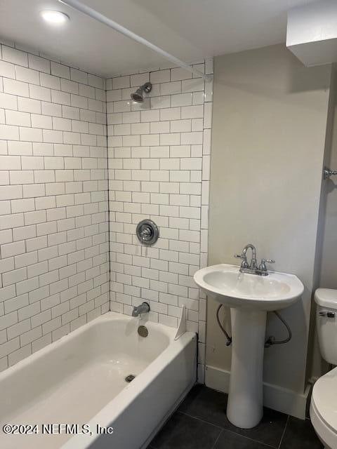 bathroom with tile patterned flooring, toilet, and tiled shower / bath