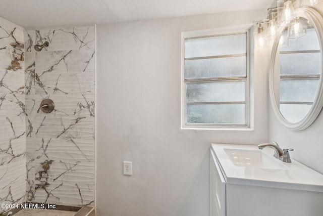 bathroom with a tile shower and vanity