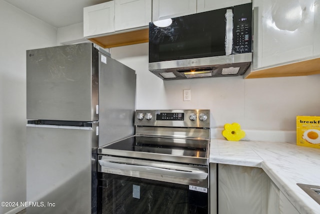 kitchen featuring light stone counters, white cabinetry, and stainless steel appliances