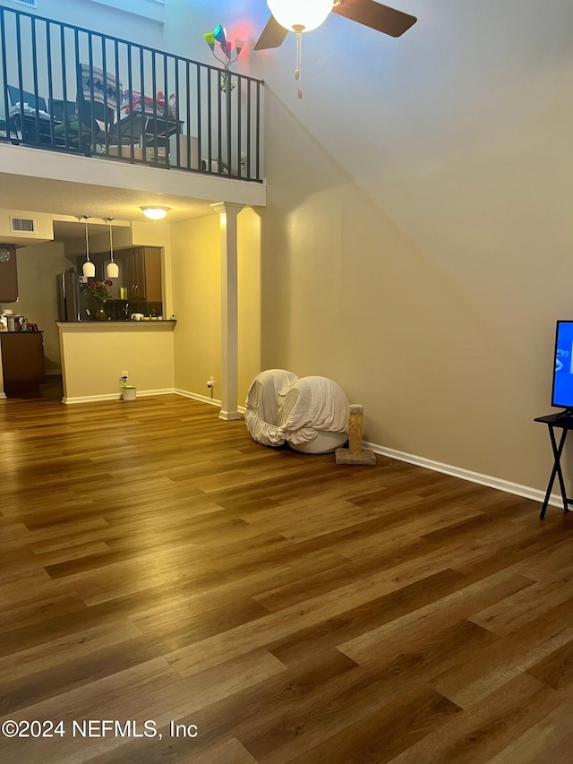 living room with hardwood / wood-style floors, ceiling fan, and a high ceiling