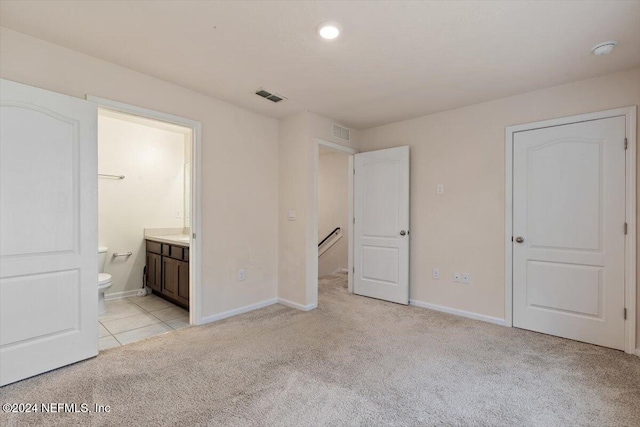 unfurnished bedroom featuring ensuite bathroom and light colored carpet