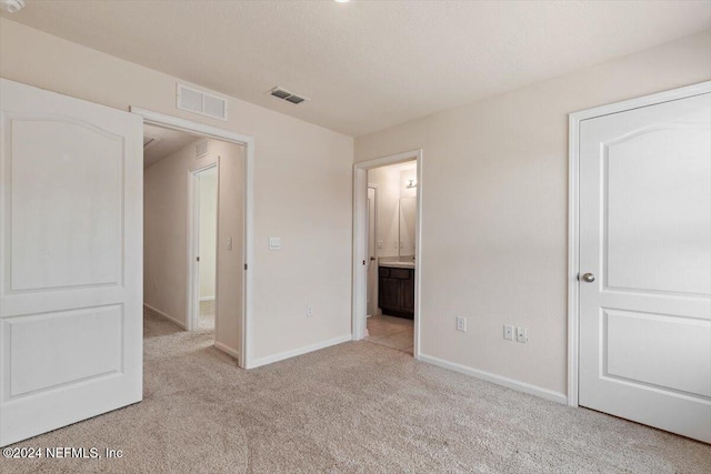 unfurnished bedroom with light carpet and ensuite bathroom