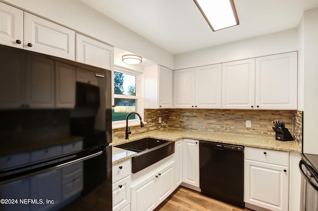 kitchen featuring decorative backsplash, sink, black appliances, white cabinets, and light hardwood / wood-style floors