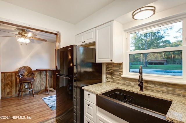 kitchen featuring white cabinets, black fridge, sink, ceiling fan, and light wood-type flooring