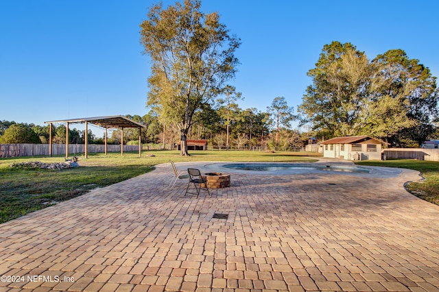 view of swimming pool with a fire pit, a pergola, an outbuilding, a yard, and a patio